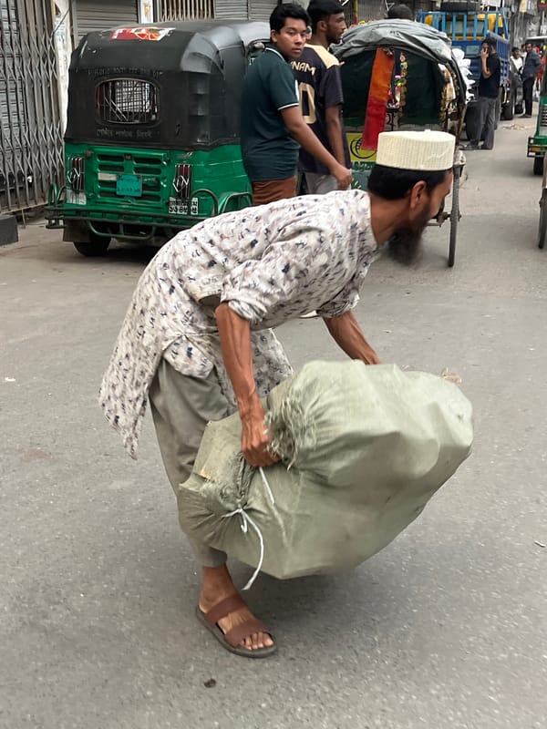 Man with sack travels by rickshaw in Dhaka