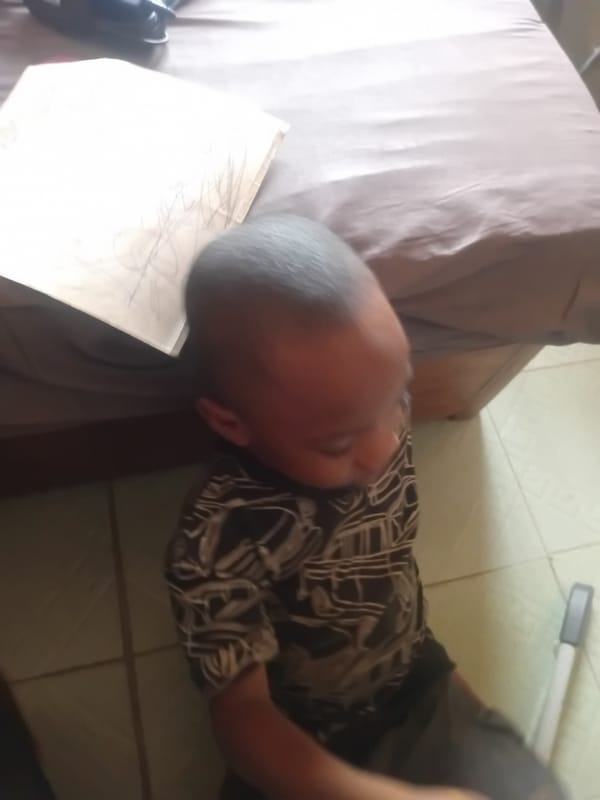 Child resting on floor against furniture edge