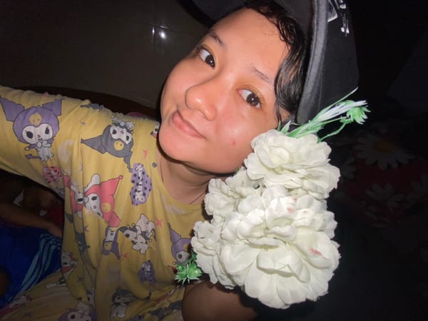 Person with flower-decorated cap holds bouquet in Gelam