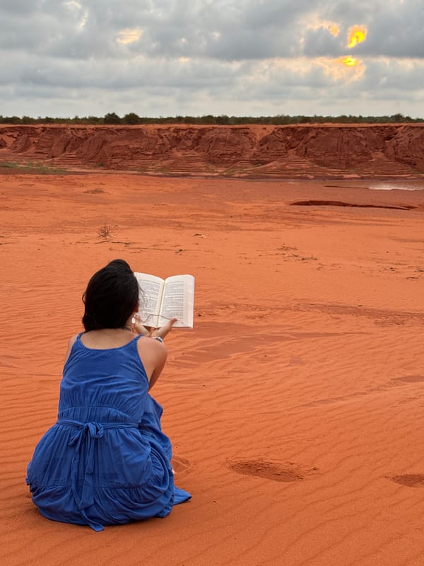 Woman reads book on red sand dunes in Vietnam