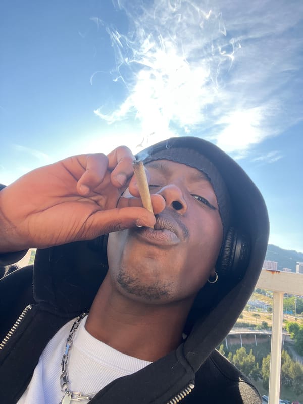 Man smoking on Barcelona balcony overlooks cityscape