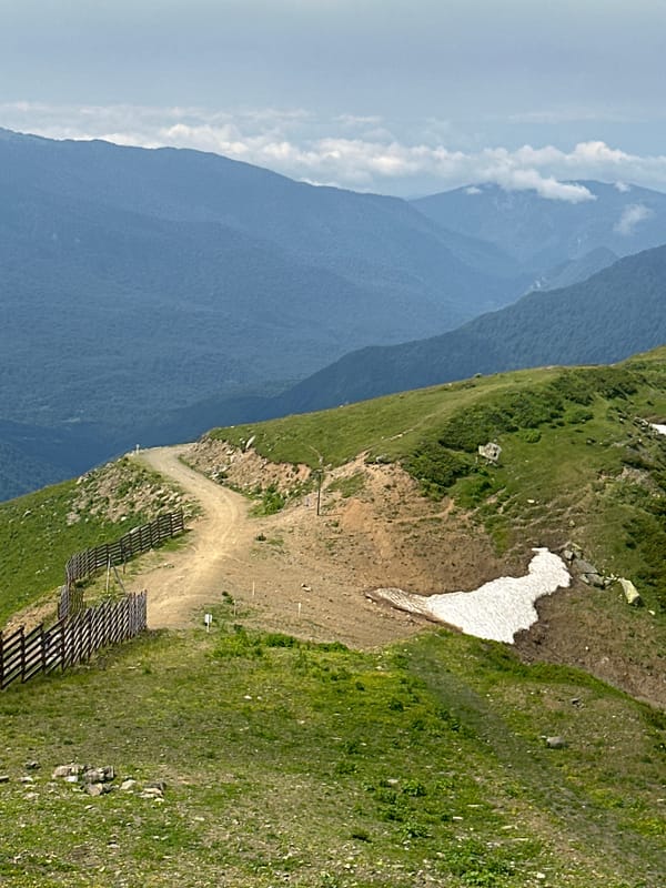 Alpine mountain terrain with trails, snow patches, and ski infrastructure