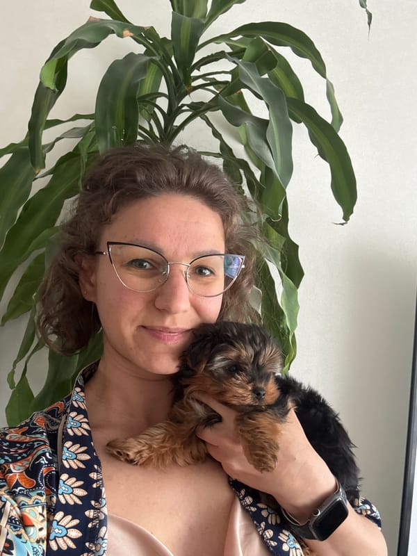 Woman with glasses holds dark puppy close