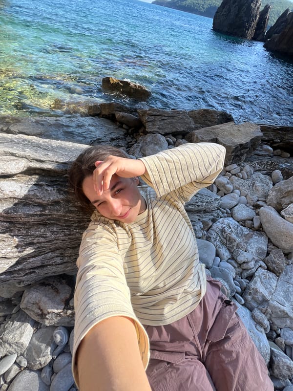 Woman rests on waterside rock in Montenegro