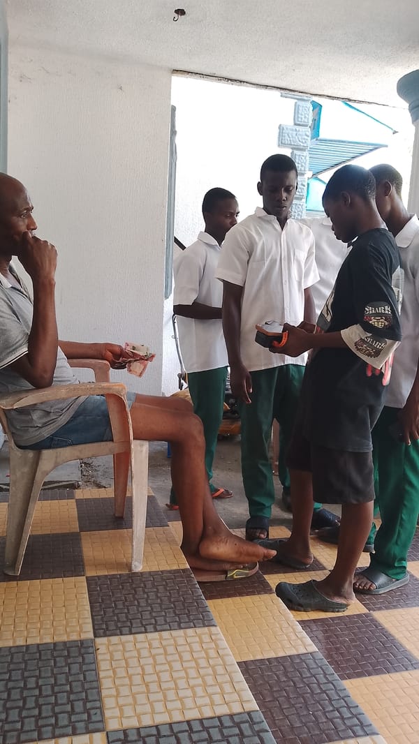 Man sits with money on porch in Asubi, Nigeria