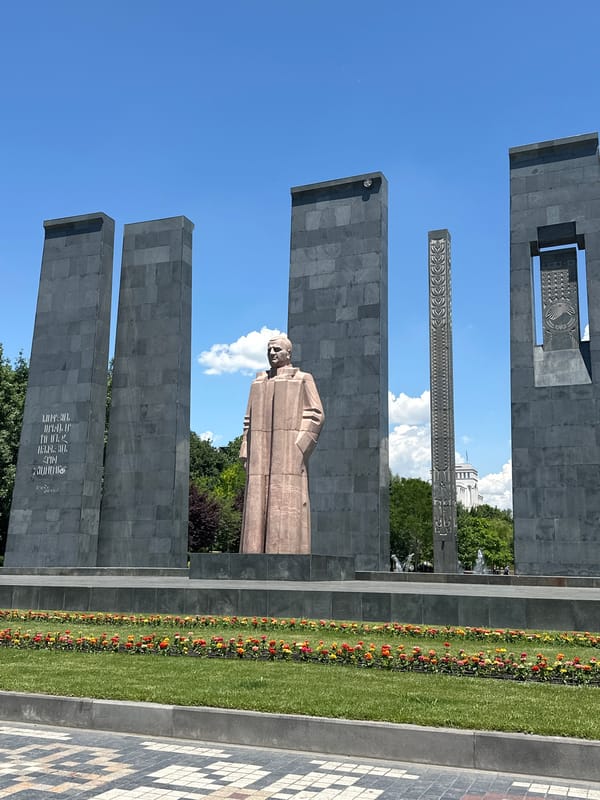 Child plays in fountain near bronze statues in Yerevan square