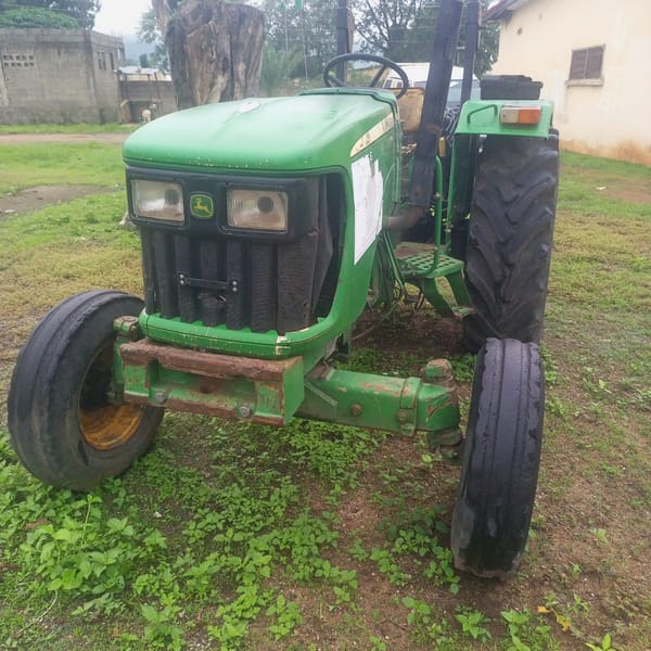 Rural compound scene in Serti with tractor, vehicles, and trees