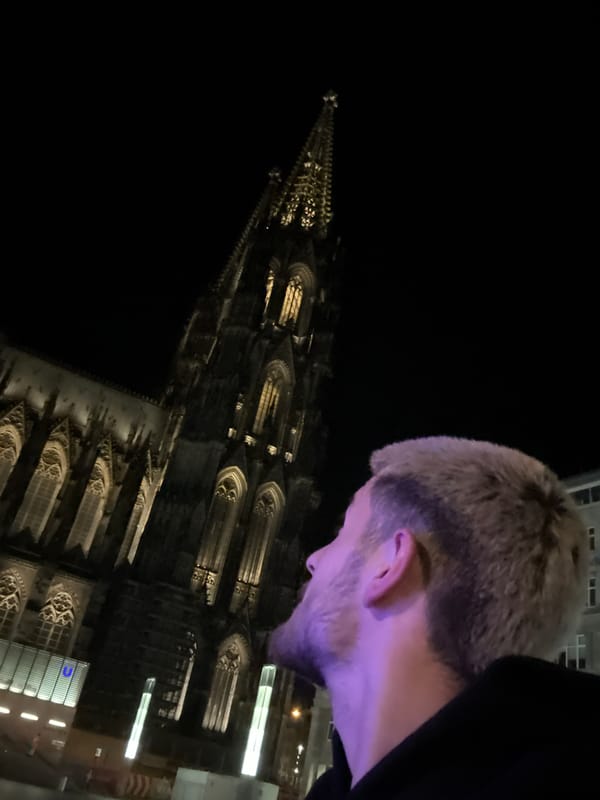 Late-night visitor documents selfies at illuminated Cologne Cathedral