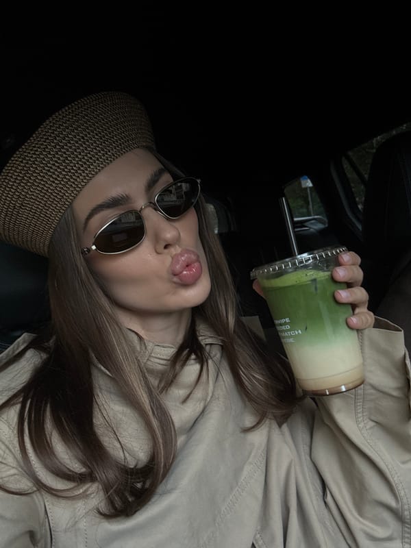 Woman poses with matcha drinks in parked car in Warsaw