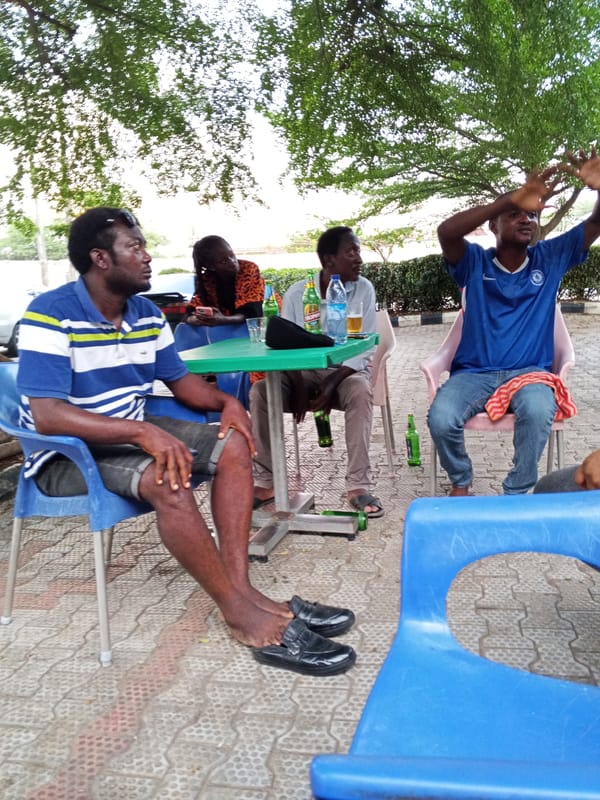 Four men gather at outdoor table in Lokoja