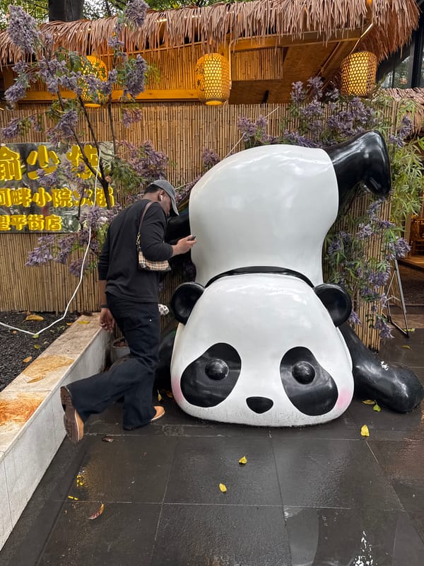 Women photographing teacups, walking on wet sidewalk in Jinjiang