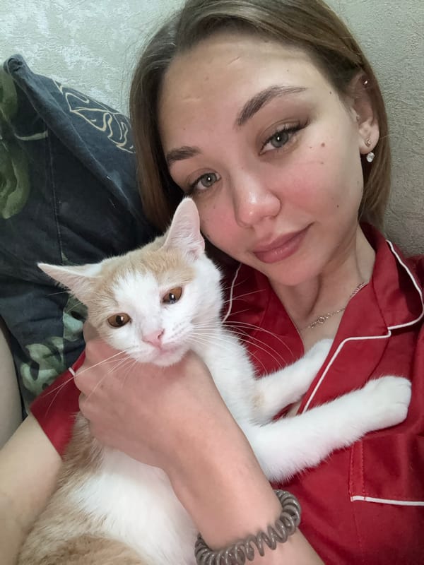 Person relaxes with white cat in red pajamas