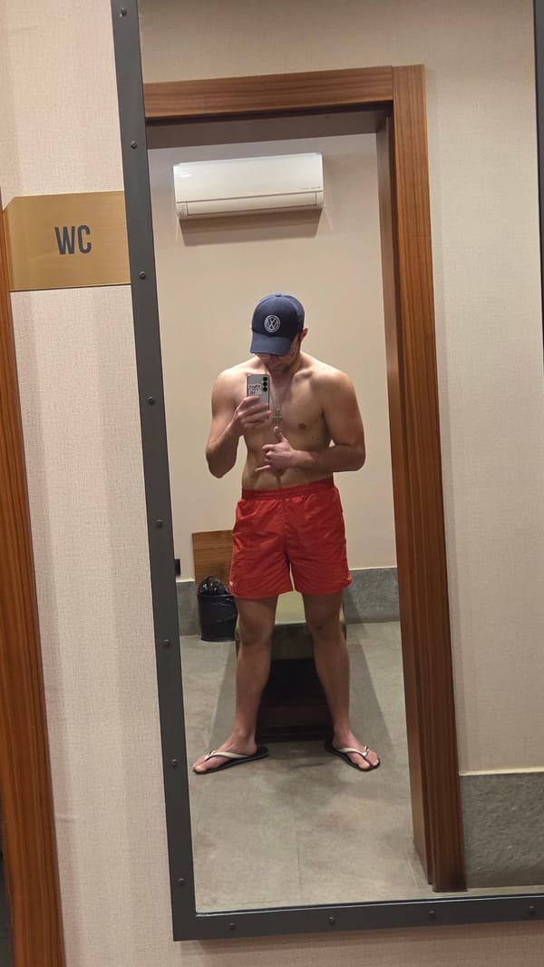 Man in lifeguard gear takes bathroom mirror selfies