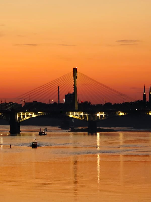 Warsaw's Vistula riverfront at golden hour, bridges and stadium lit up