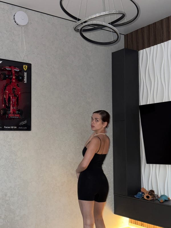 Woman poses with cat in Russian home featuring Ferrari poster