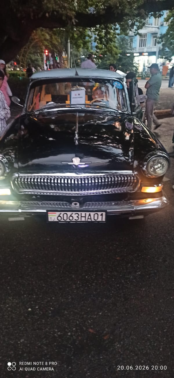 Evening motorcycle meetup with a street event and vintage cars