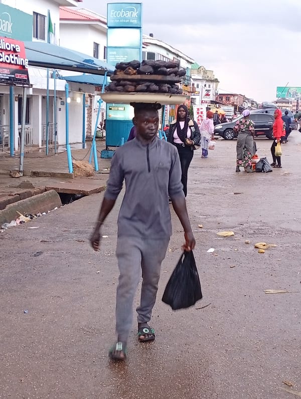 Wet afternoon street life along a Jos market corridor