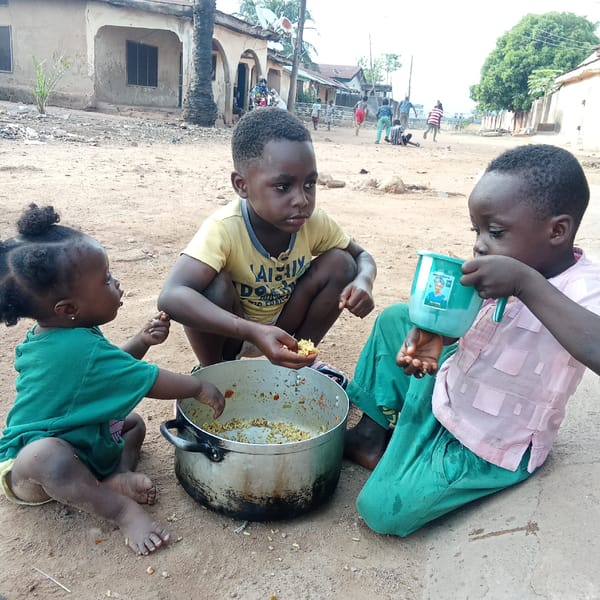 Children share outdoor meal from pot in Akwanga, Nigeria