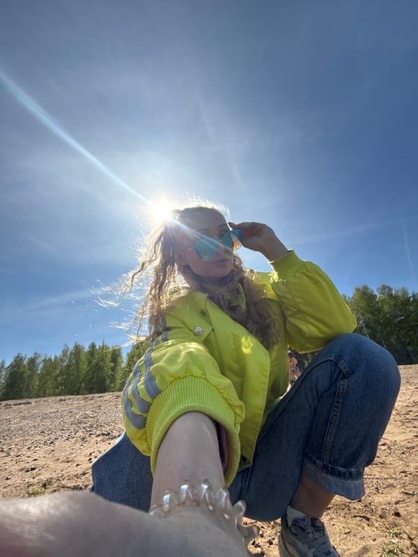 Young person sits in sunny sandy area in Chaikovsky