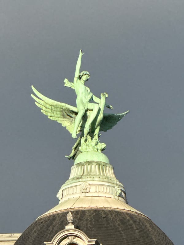 Green angelic statue observed on classical Paris architecture