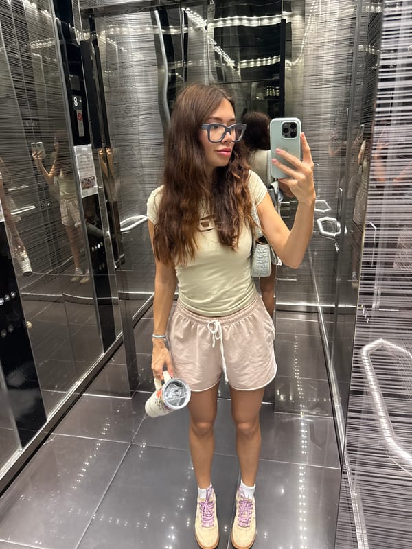Woman takes elevator selfie while holding cup