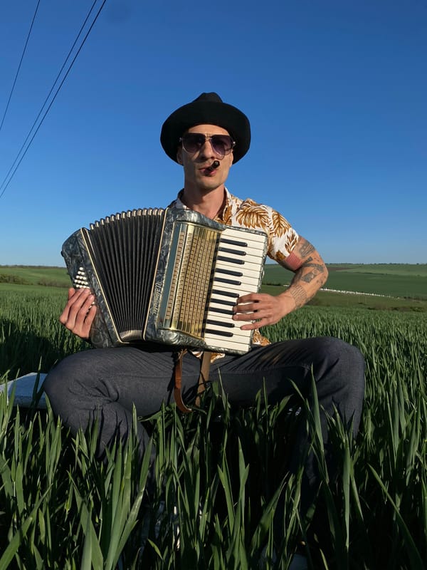 Accordion player performs in Bulgarian field under blue skies