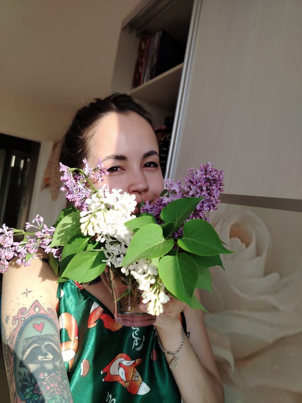 Woman displays lilac bouquet in vase indoors