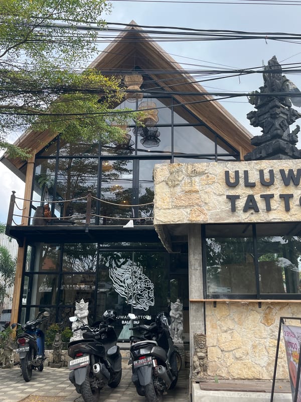 Tattoo parlor exterior and Balinese statuary documented in Kuta