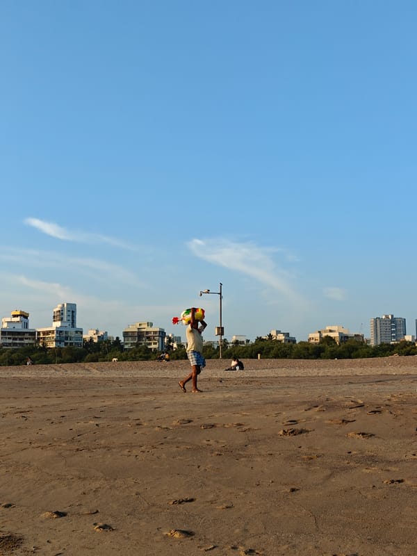 Beach vendors carry goods along Mumbai shoreline
