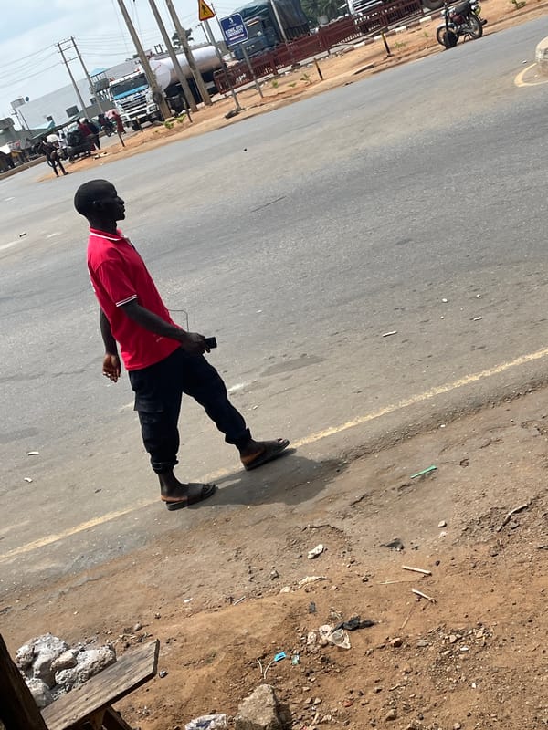 Man walks roadside with phone in Akwanga, Nigeria