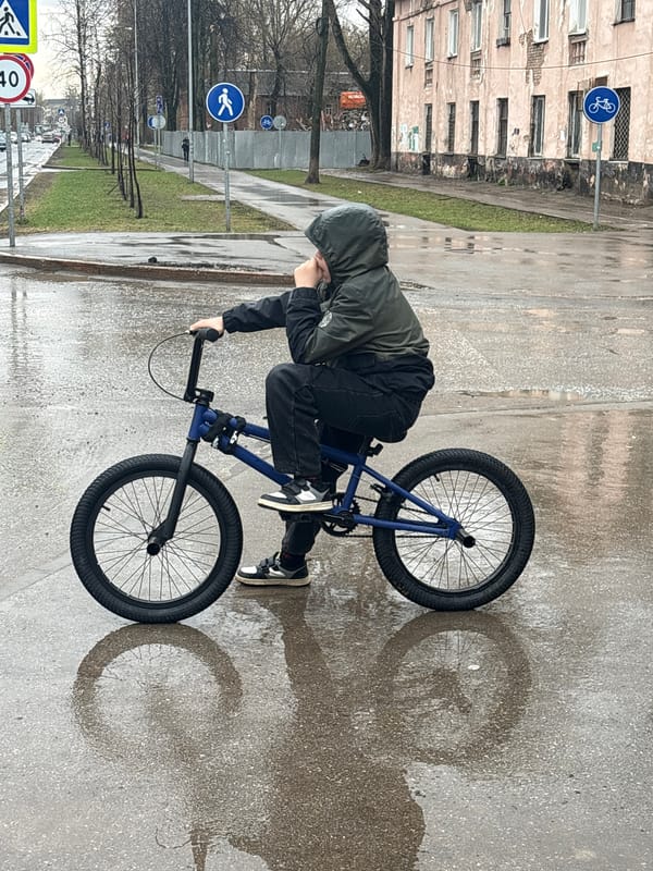 BMX rider balances on wet sidewalk in Perm