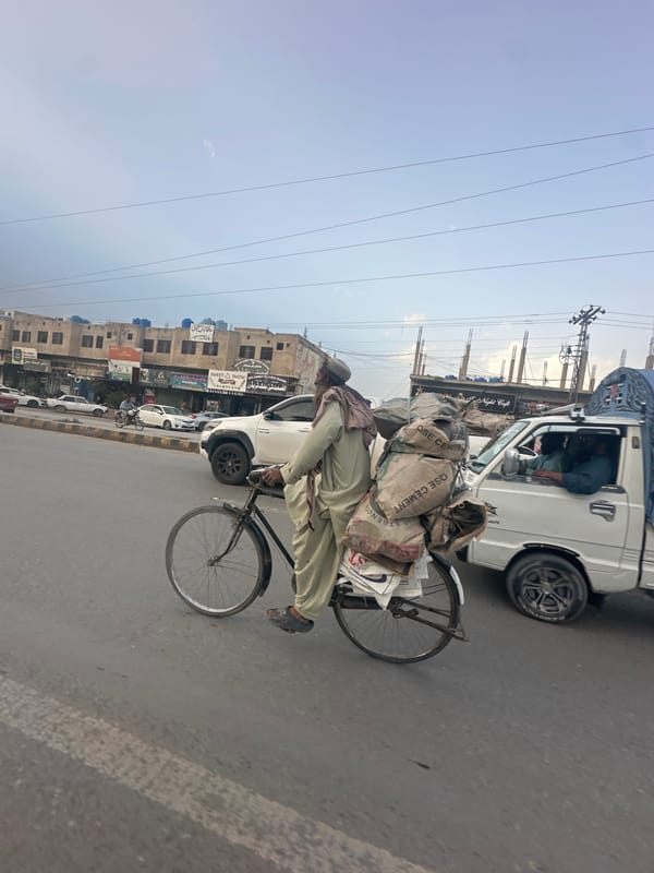 Cyclist transports cement bags on overloaded bicycle in Quetta