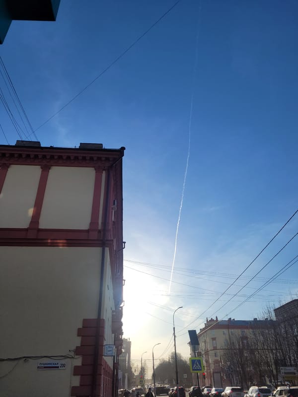 Upward street view captured in Izhevsk showing contrail overhead
