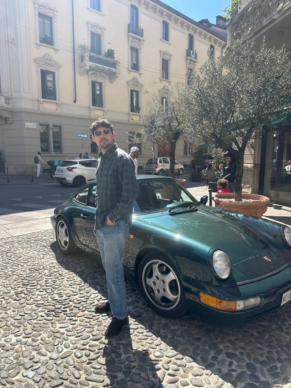 Man poses with green Porsche on Milan cobblestone street