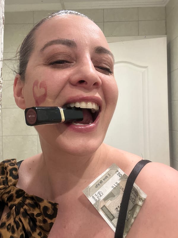 Woman applies makeup in Riga bathroom, Indian currency visible