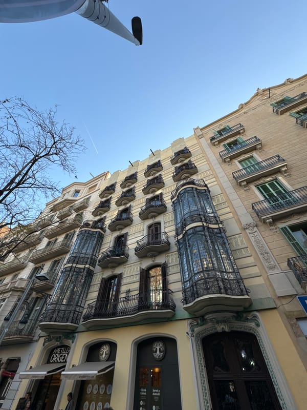 Cyclist rides red bike past ornate Barcelona buildings