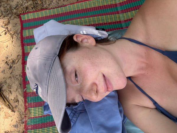 Woman relaxes on beach mat in early morning Thailand