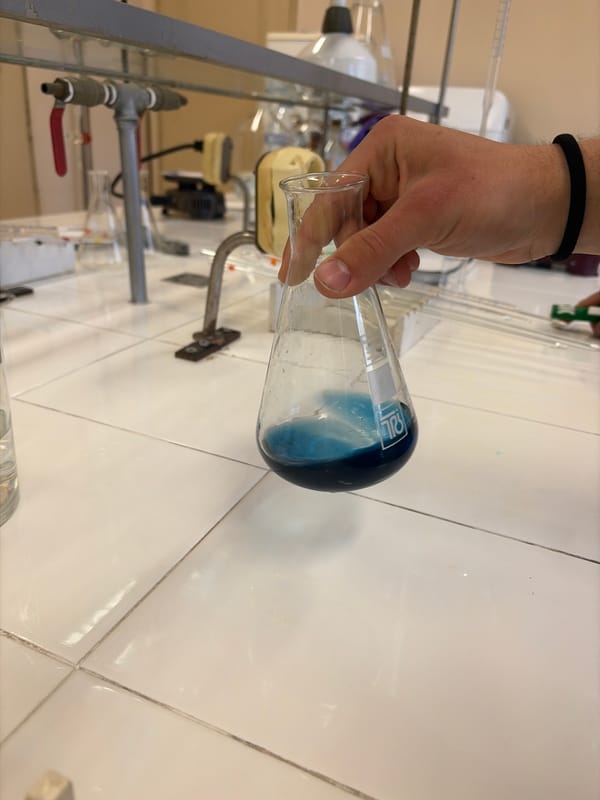 Person handles blue liquid in laboratory flask
