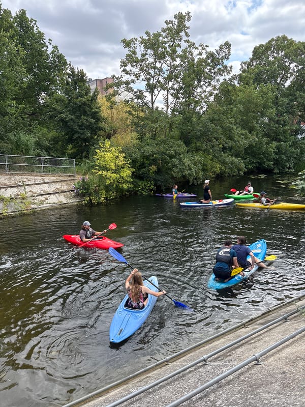 Kayaking on an urban river surrounded by wild green edges