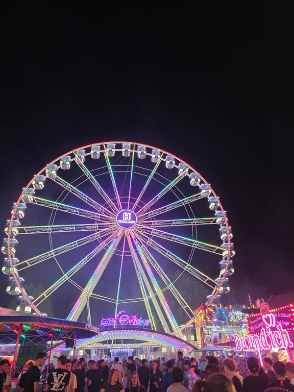 Rainbow-lit Ferris wheel with 'H' symbol draws crowds in Salzburg