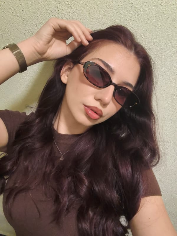 Woman takes indoor selfies wearing brown shirt and sunglasses