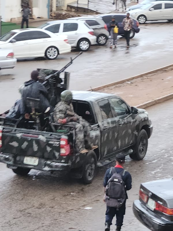 Armed military-style truck and personnel on wet urban street