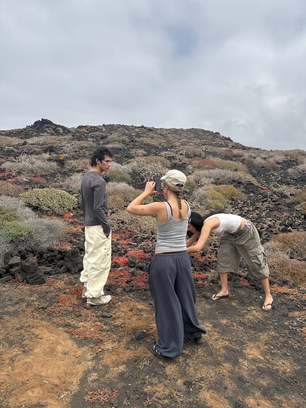 Three people gather on volcanic terrain in Tinajo