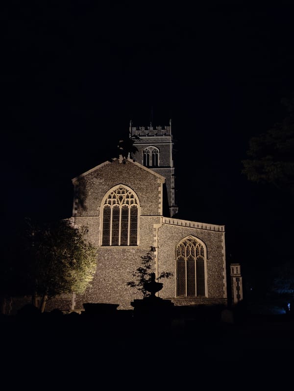 Stone church illuminated by spotlights at night in East Suffolk