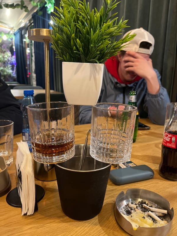 Person in white cap at Sofia bar table with green bottle