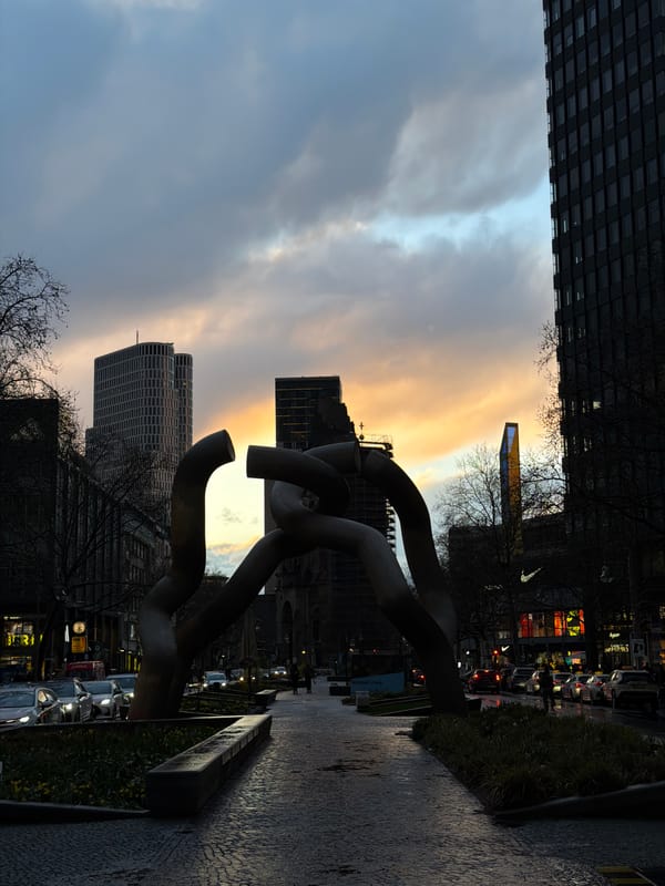 Metal sculpture photographed against modern Berlin architecture backdrop