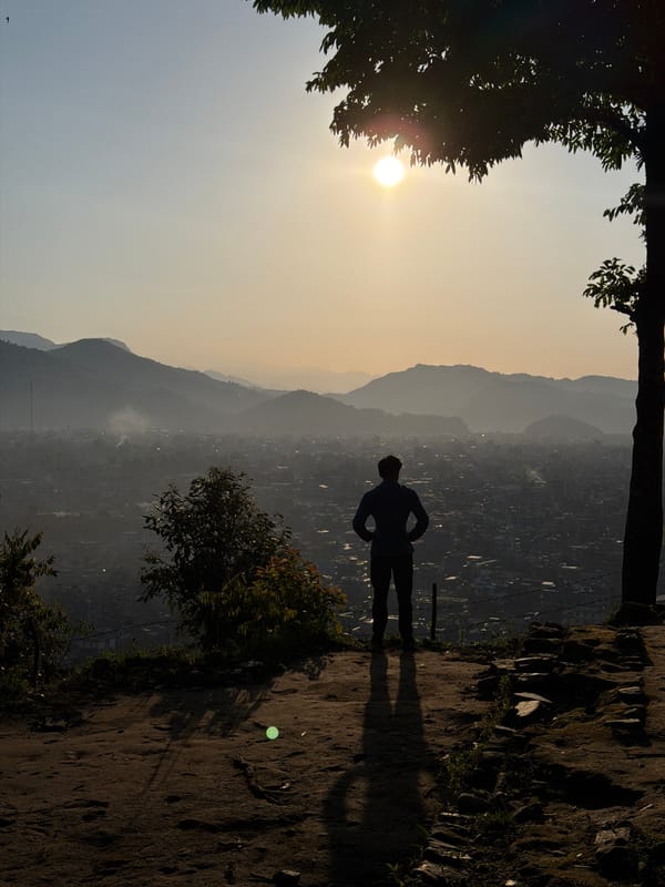 Person stands on cliff edge during sunrise in Pokhara