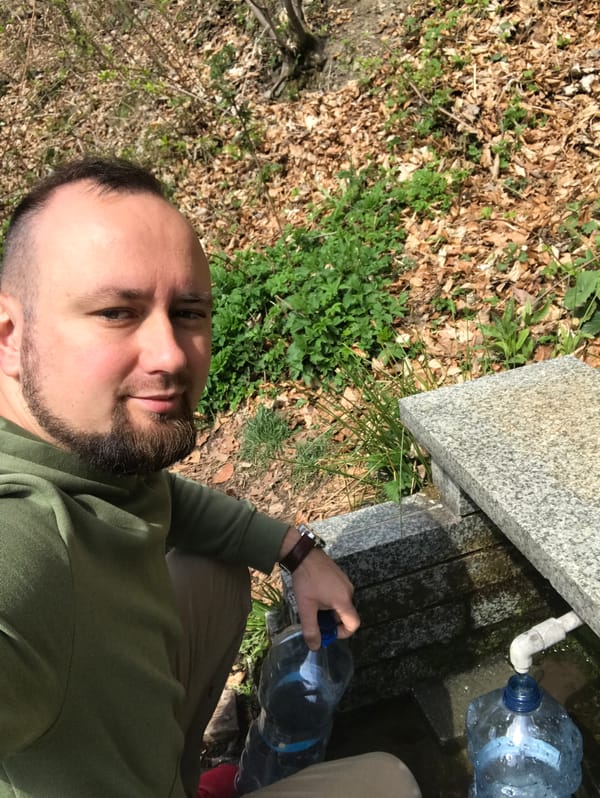 Man fills water bottle at stone fountain in Wisła