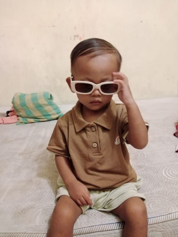 Oversized sunglasses and a raised hand on a mattress in Pati