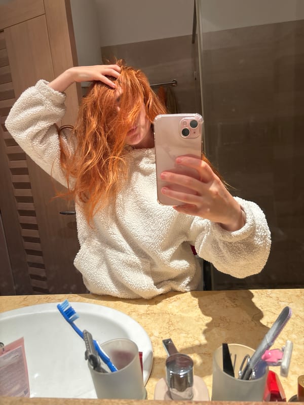 Woman multitasks with phone during bathroom routine in Budva